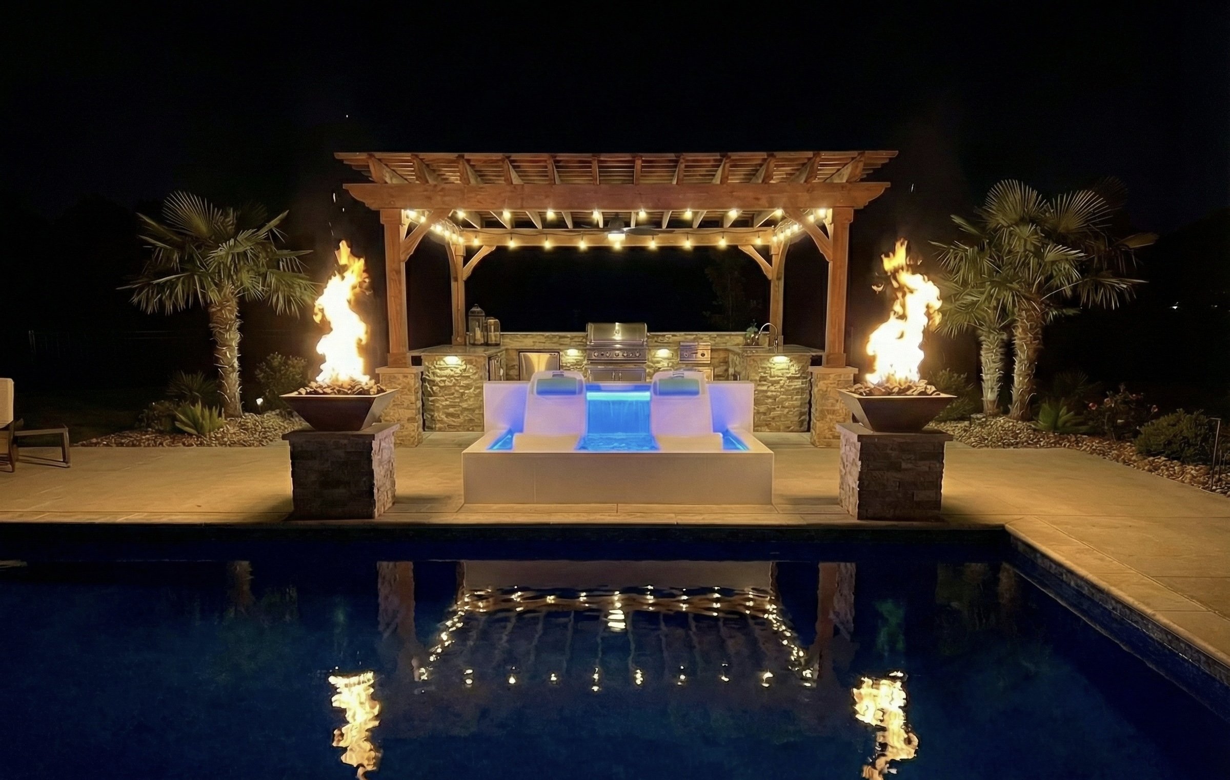 Freestanding Baja ledge with fire bowls and pergola at night